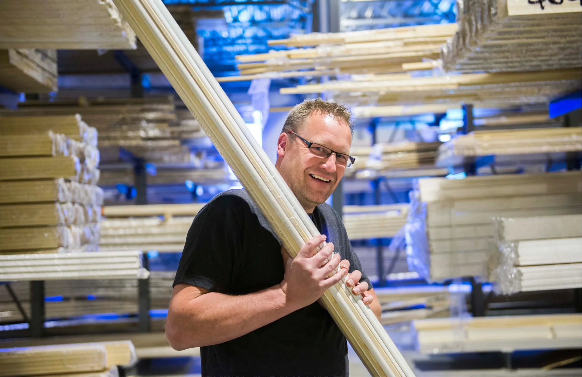 Combiwood worker carrying wooden mouldings in warehouse